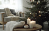  A cosy living room scene featuring Scandinavian Christmas decor, with a soft knit throw, glowing white candles, and a minimal Christmas tree adorned with simple ornaments, creating a warm and inviting atmosphere.